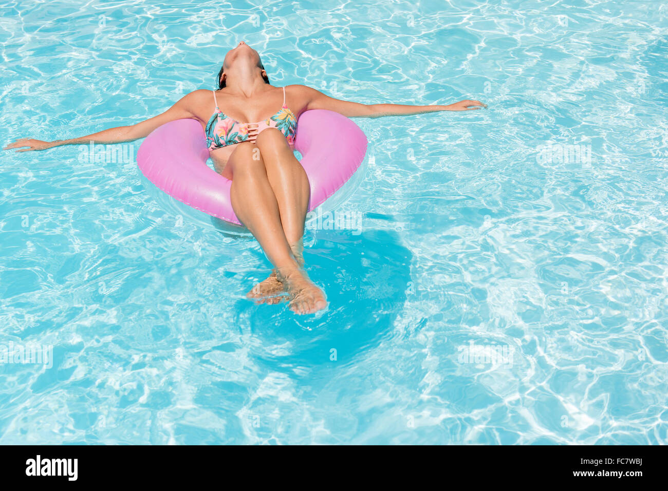 Caucasian woman floating in swimming pool Stock Photo
