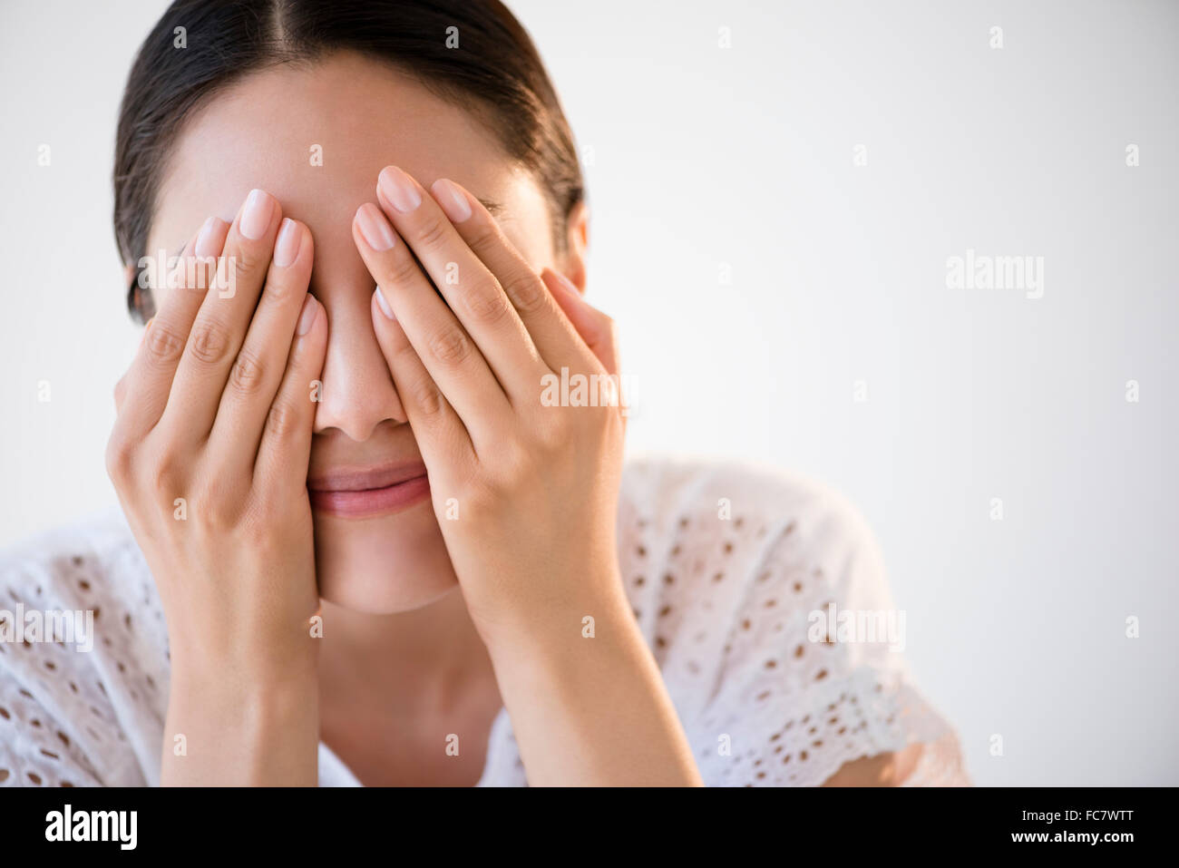 Hispanic woman covering her eyes Stock Photo