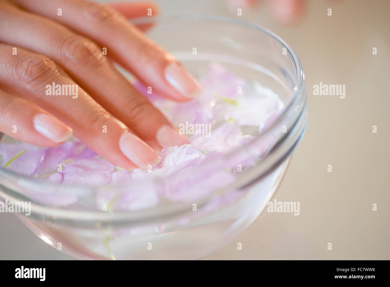 Close up of Hispanic woman soaking her nails Stock Photo