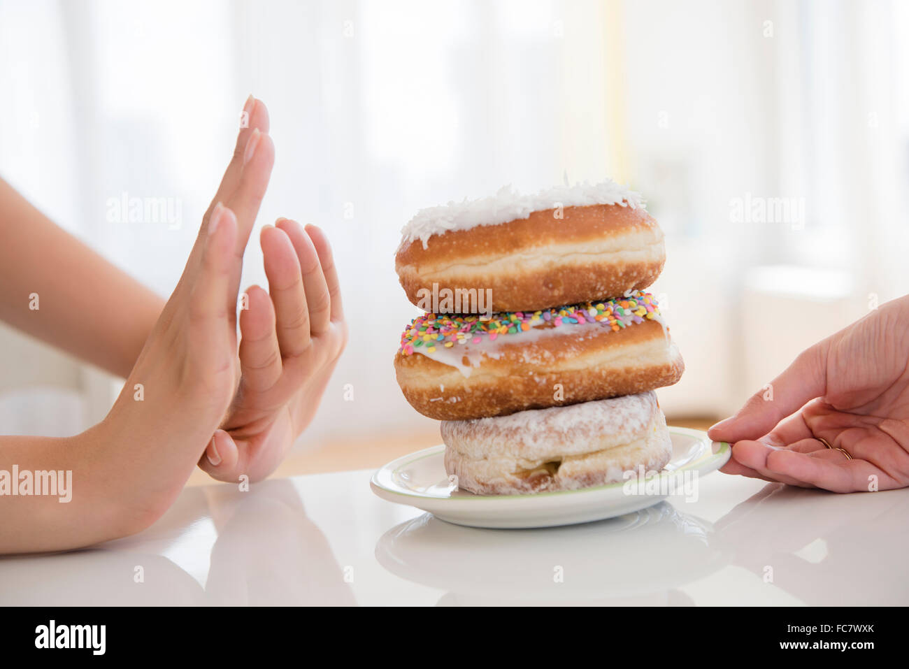 Woman refusing plate of donuts Stock Photo