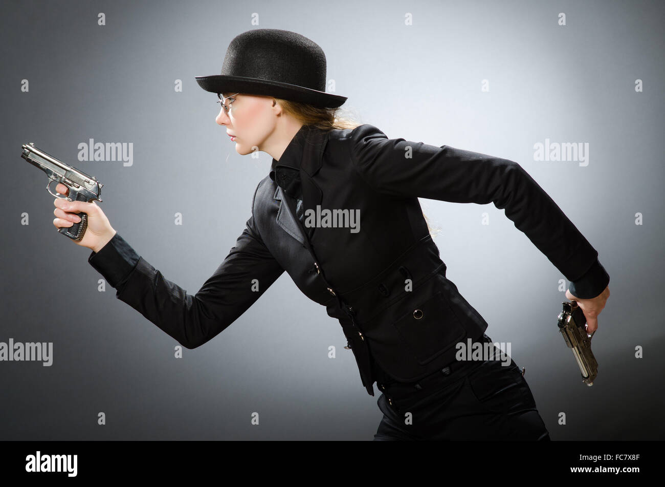 Female spy with weapon against gray Stock Photo