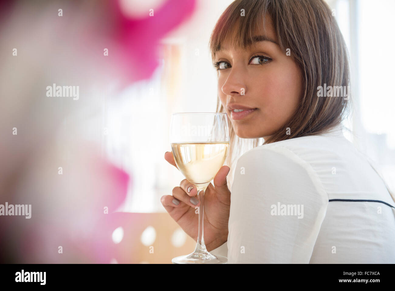 Mixed race woman drinking white wine Stock Photo