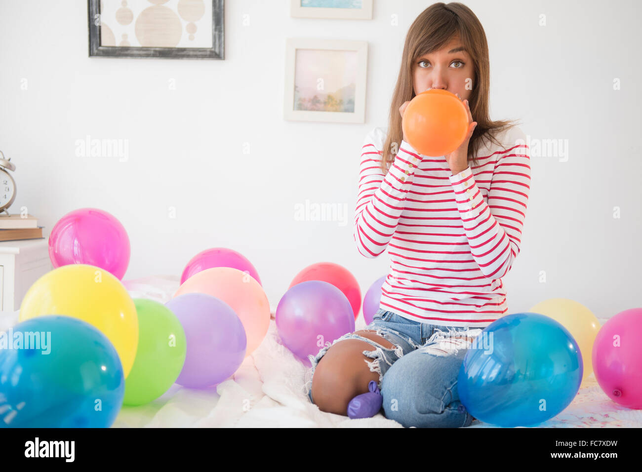 Mixed race woman blowing up balloons Stock Photo