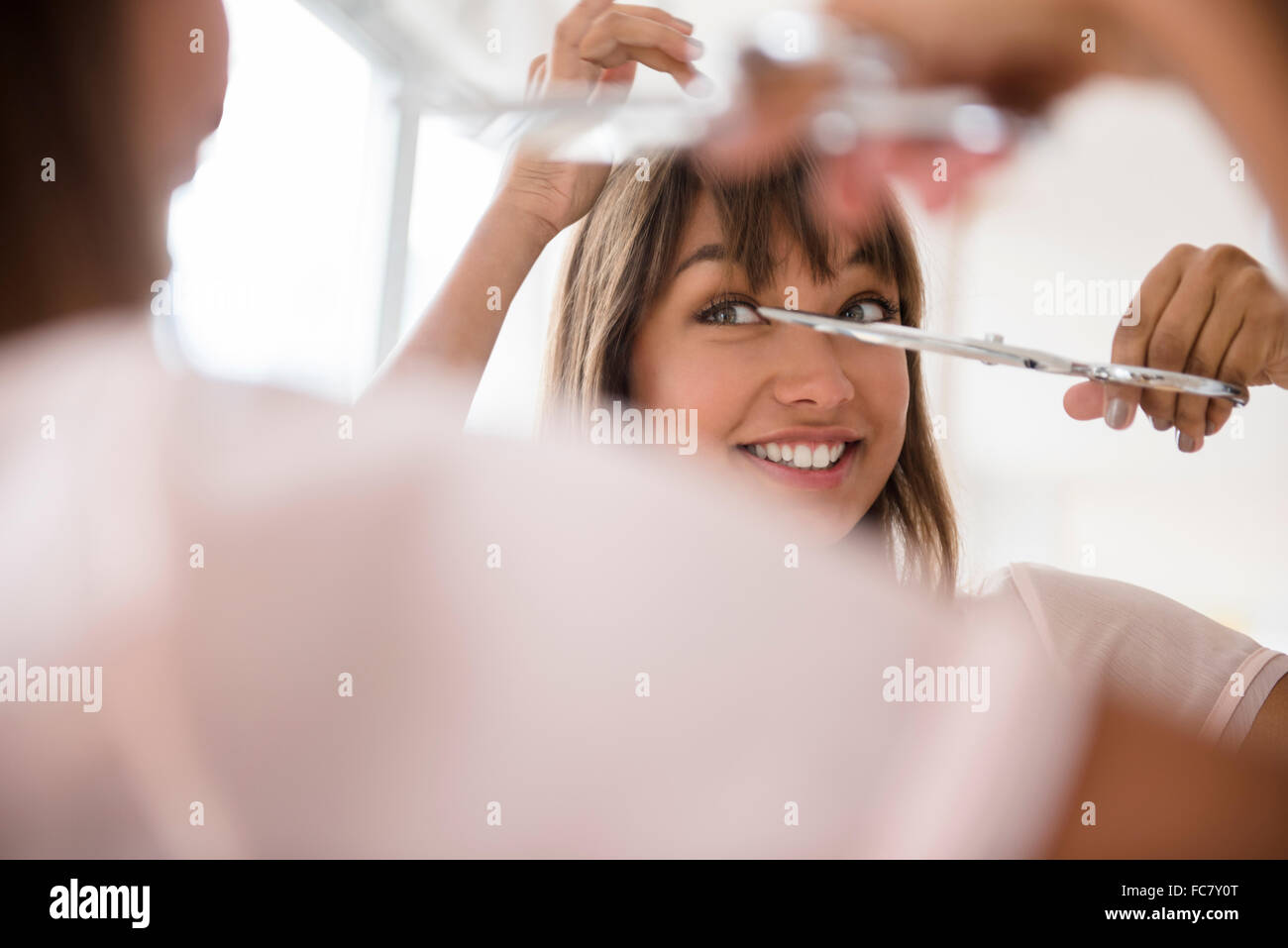 Mixed race woman trimming her bangs Stock Photo