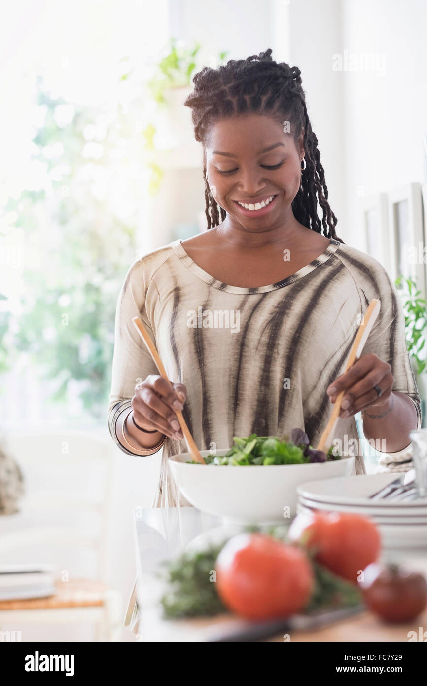 Black woman tossing salad in kitchen Stock Photo