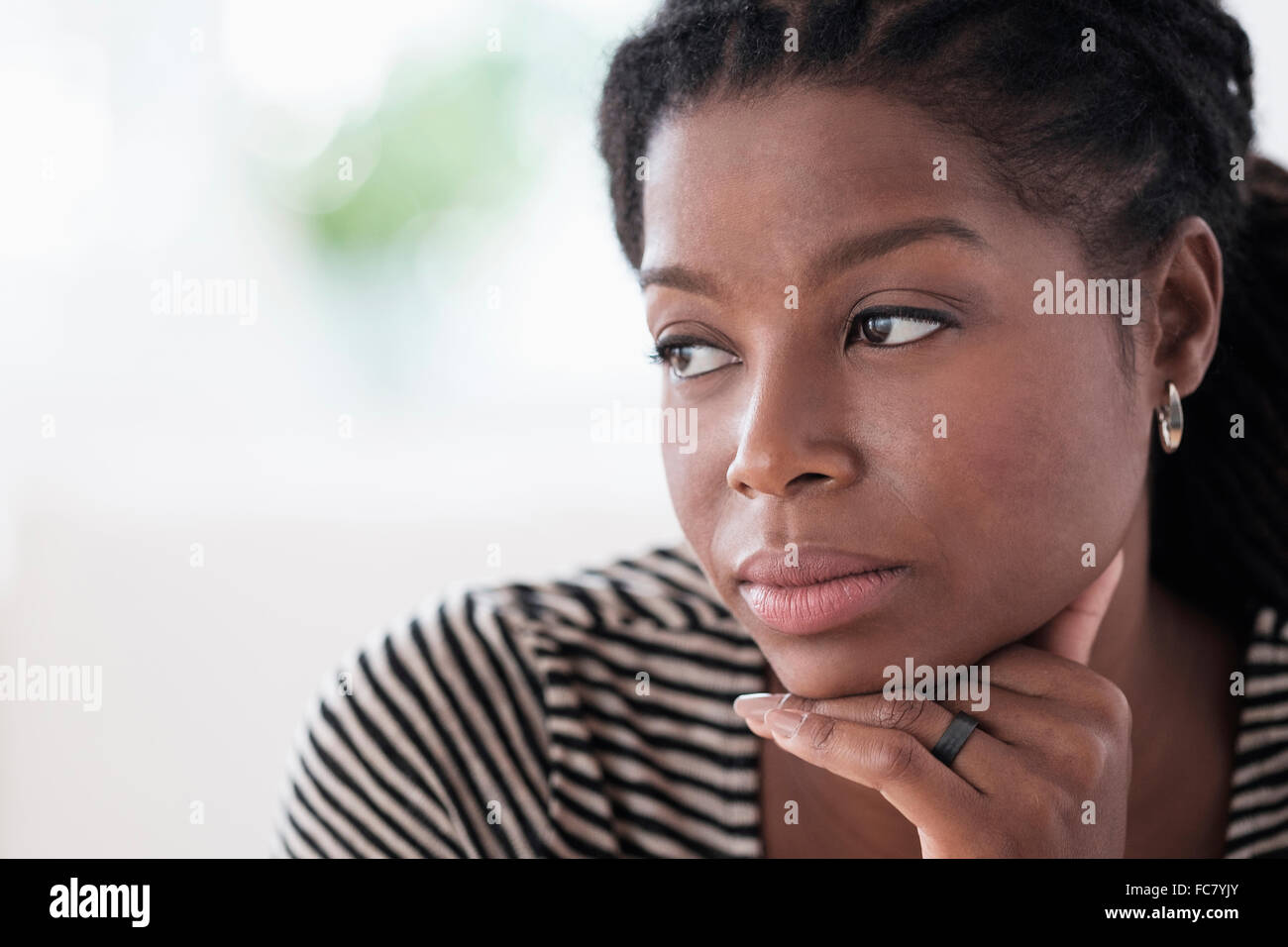 Black woman resting chin in hand Stock Photo