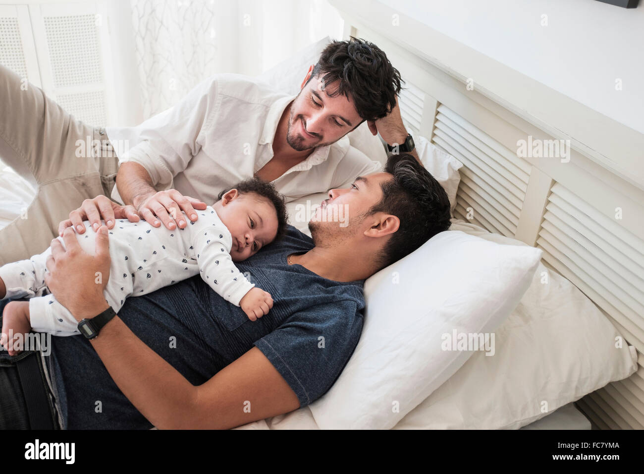 Gay fathers relaxing with baby son on bed Stock Photo