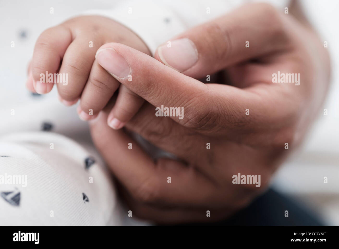Close up of father holding hand of baby son Stock Photo