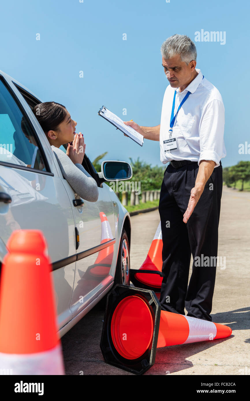 female learner driver apologising to angry instructor after running over traffic cone Stock Photo