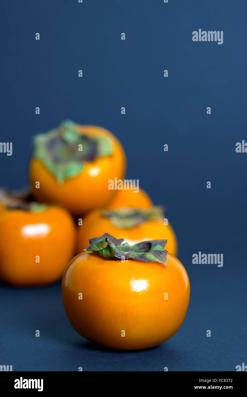 Persimmons on blue background Stock Photo