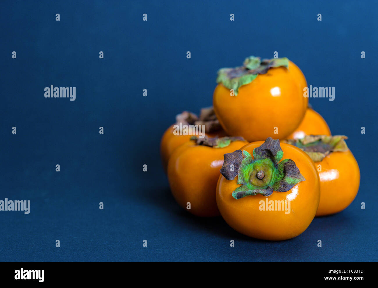 Persimmons on blue background Stock Photo