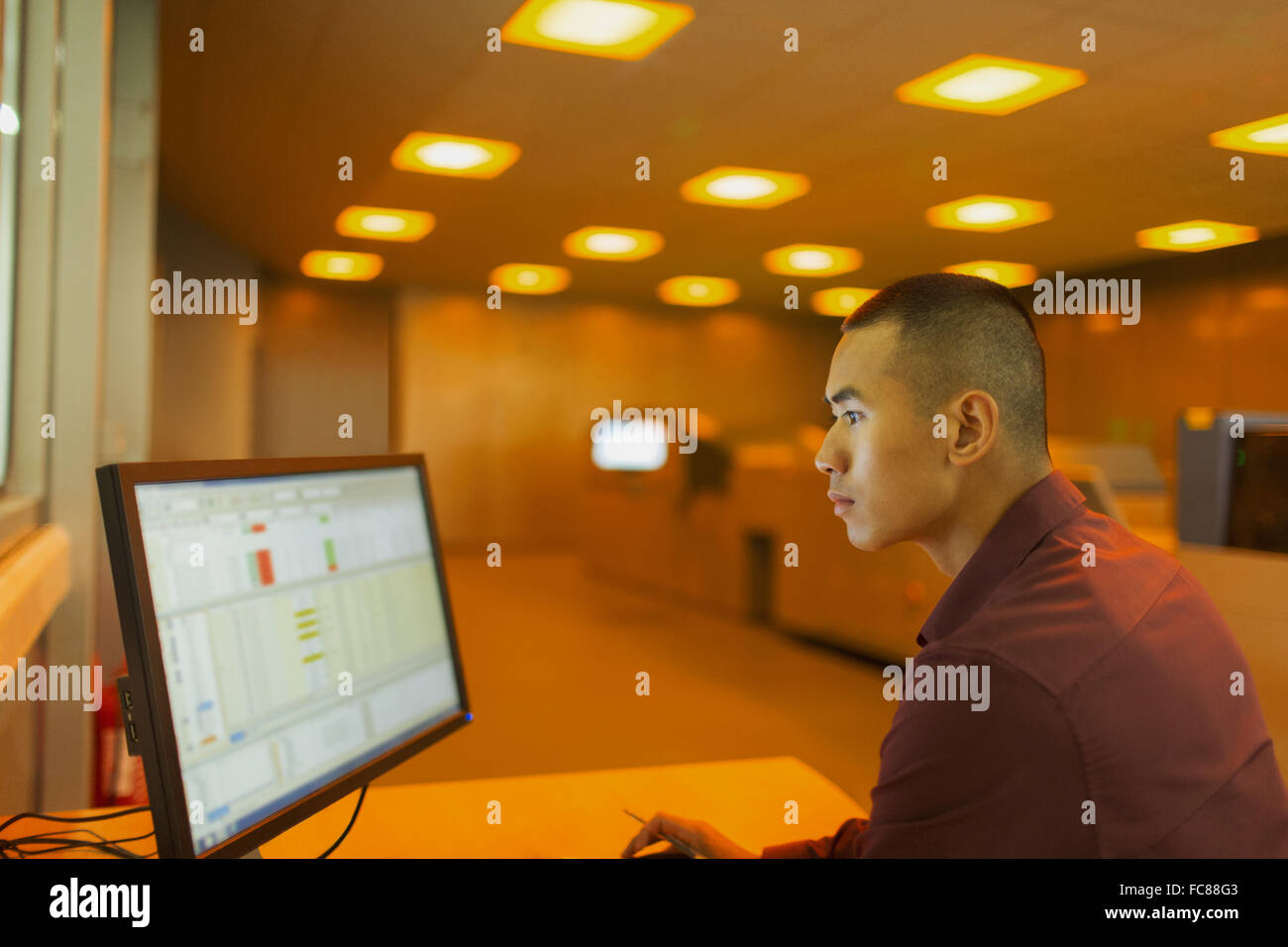 Engineer working at computer in factory control room Stock Photo