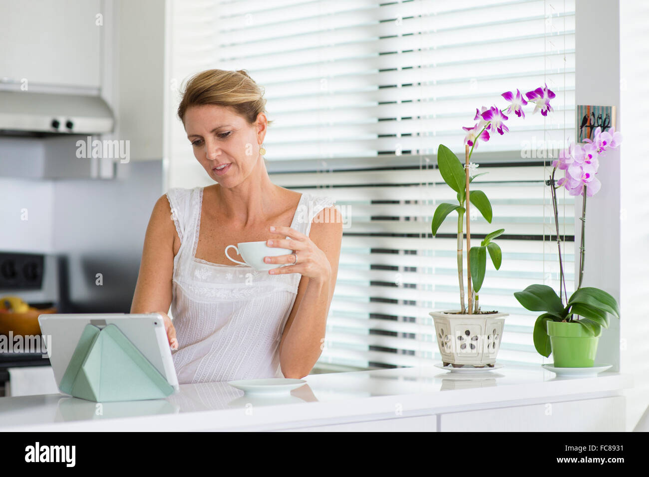 Caucasian woman using digital tablet in kitchen Stock Photo