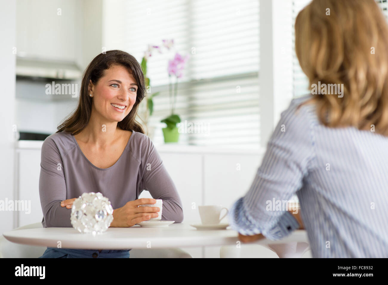 Caucasian women drinking coffee in kitchen Stock Photo