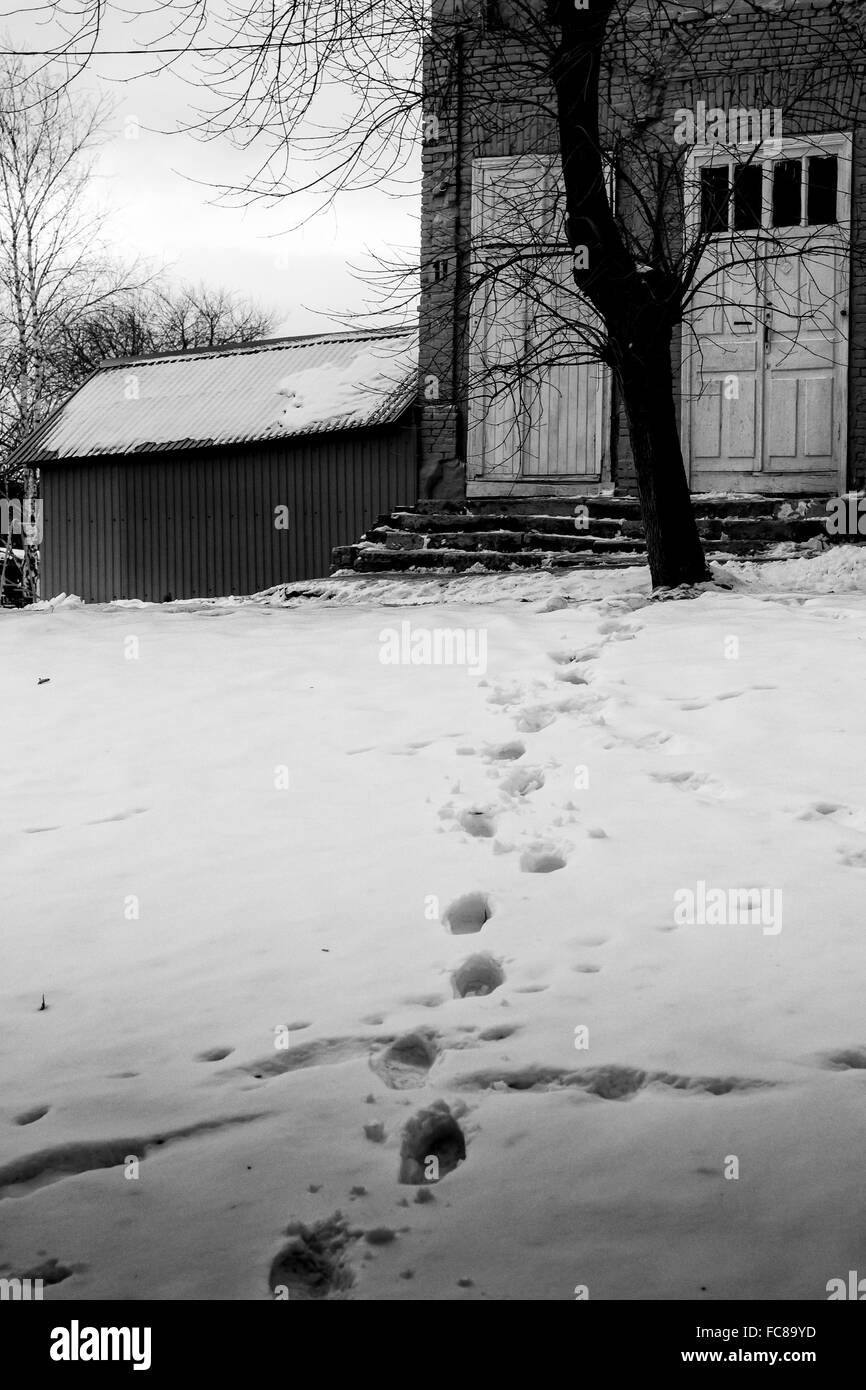 Set of human footprints in the snow lead towards the comfort of a home