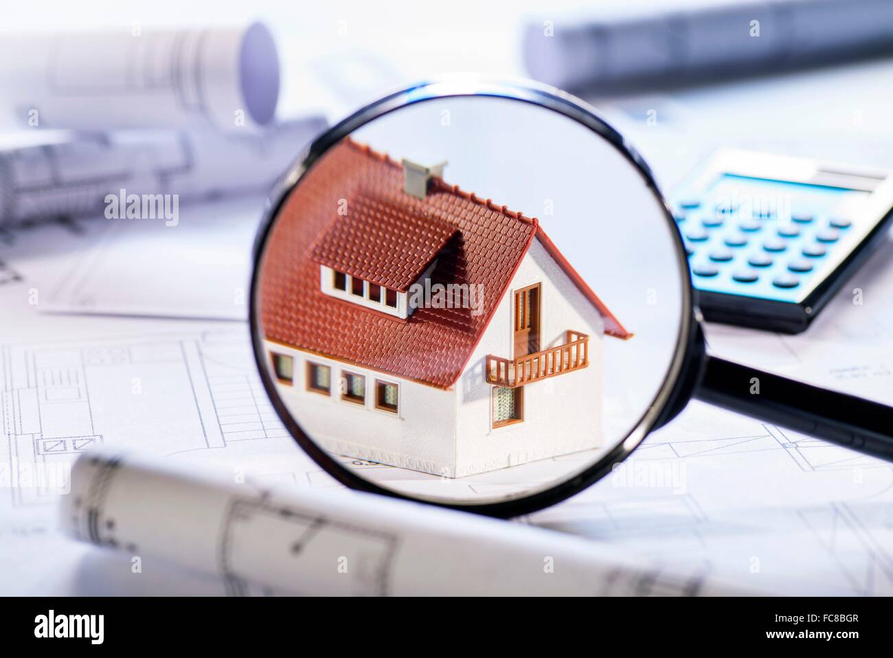 House under a magnifier with building plans and calculator Stock Photo