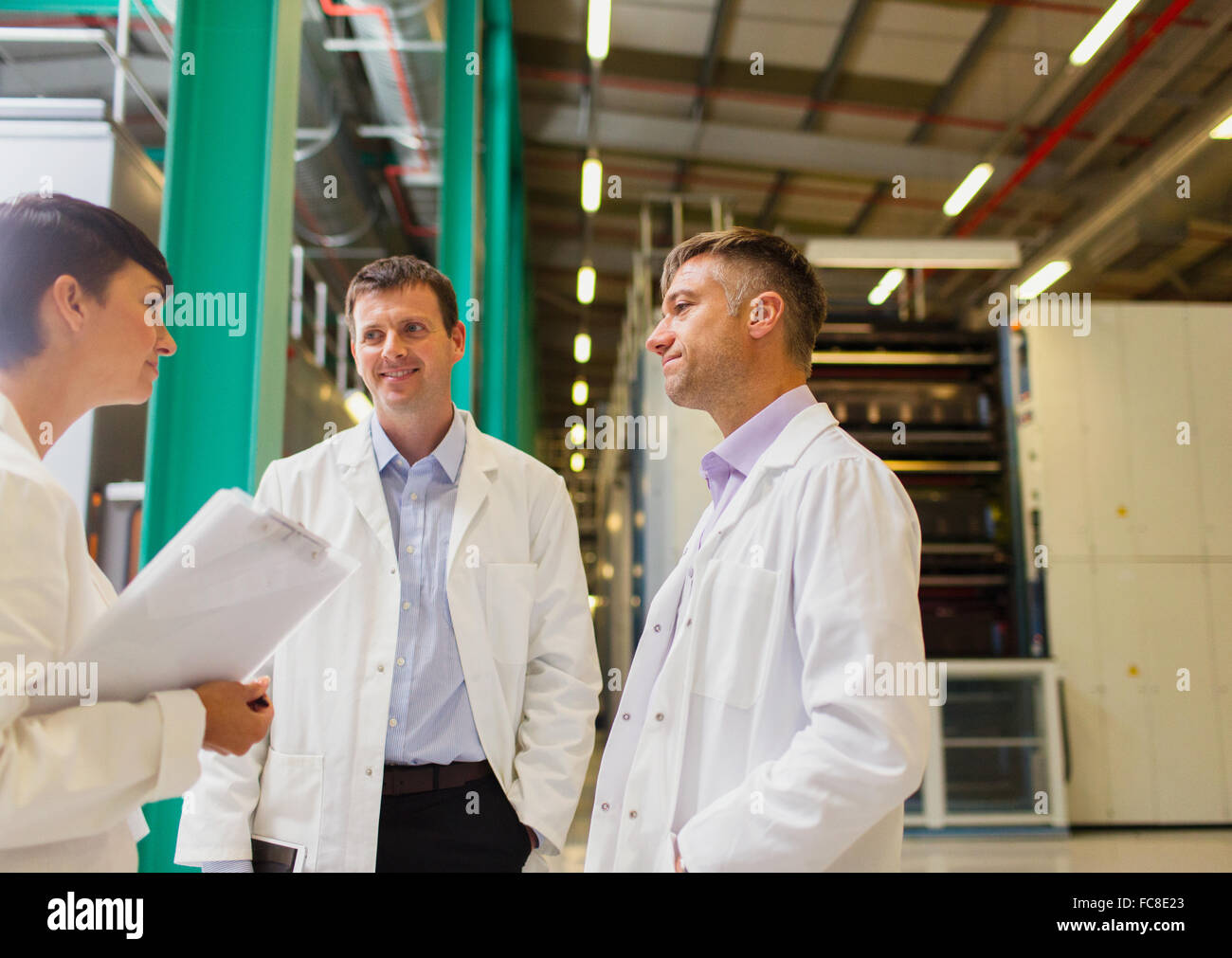 Scientists and businesswoman talking in factory Stock Photo