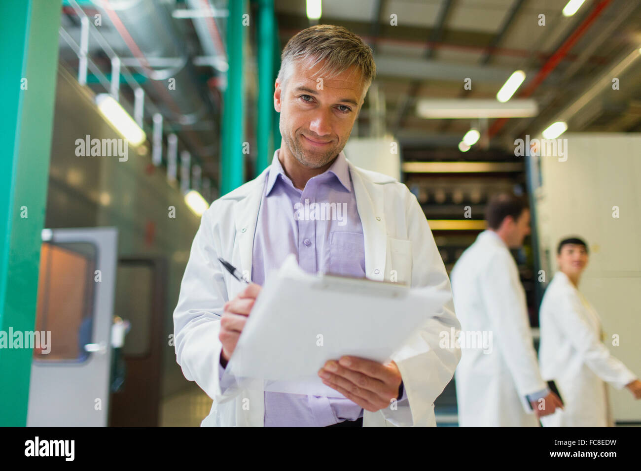 Portrait confident scientist with clipboard in factory Stock Photo