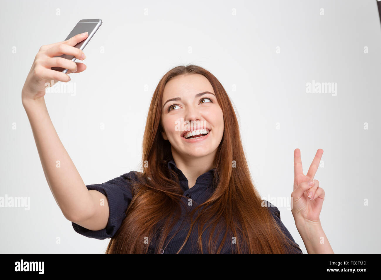 Smiling pretty young woman taking selfie with mobile phone and showing ...