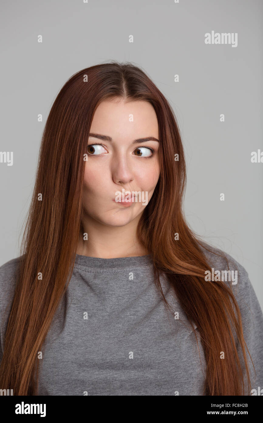 Portrait of amusing confused young woman with long hair over grey background Stock Photo