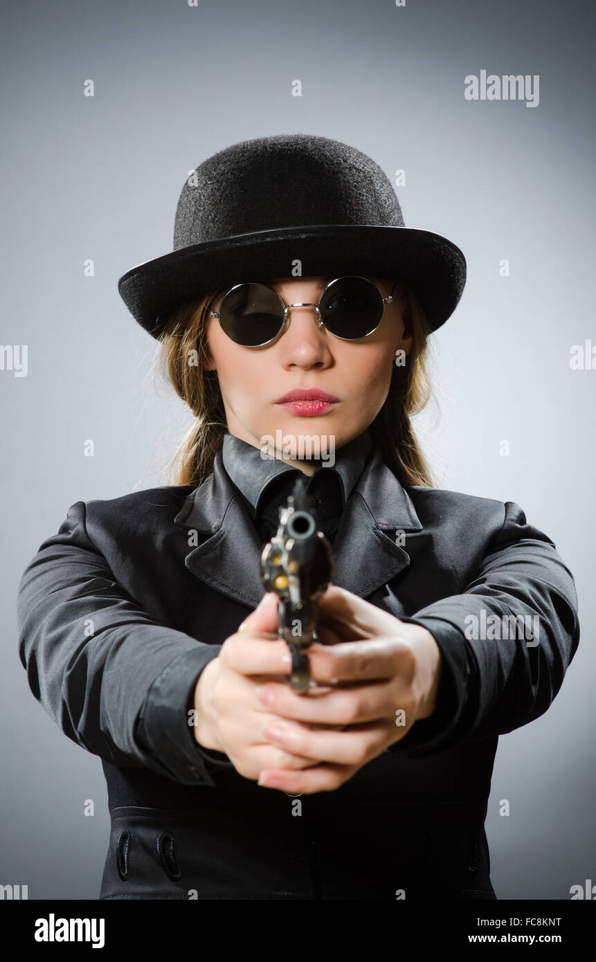 Female spy with weapon against gray Stock Photo