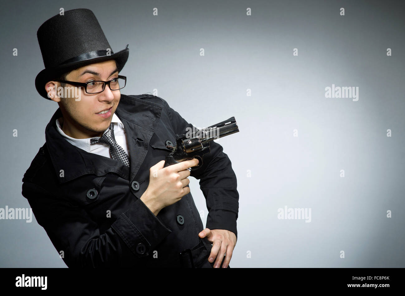 Criminal in black coat holding hadgun against gray Stock Photo