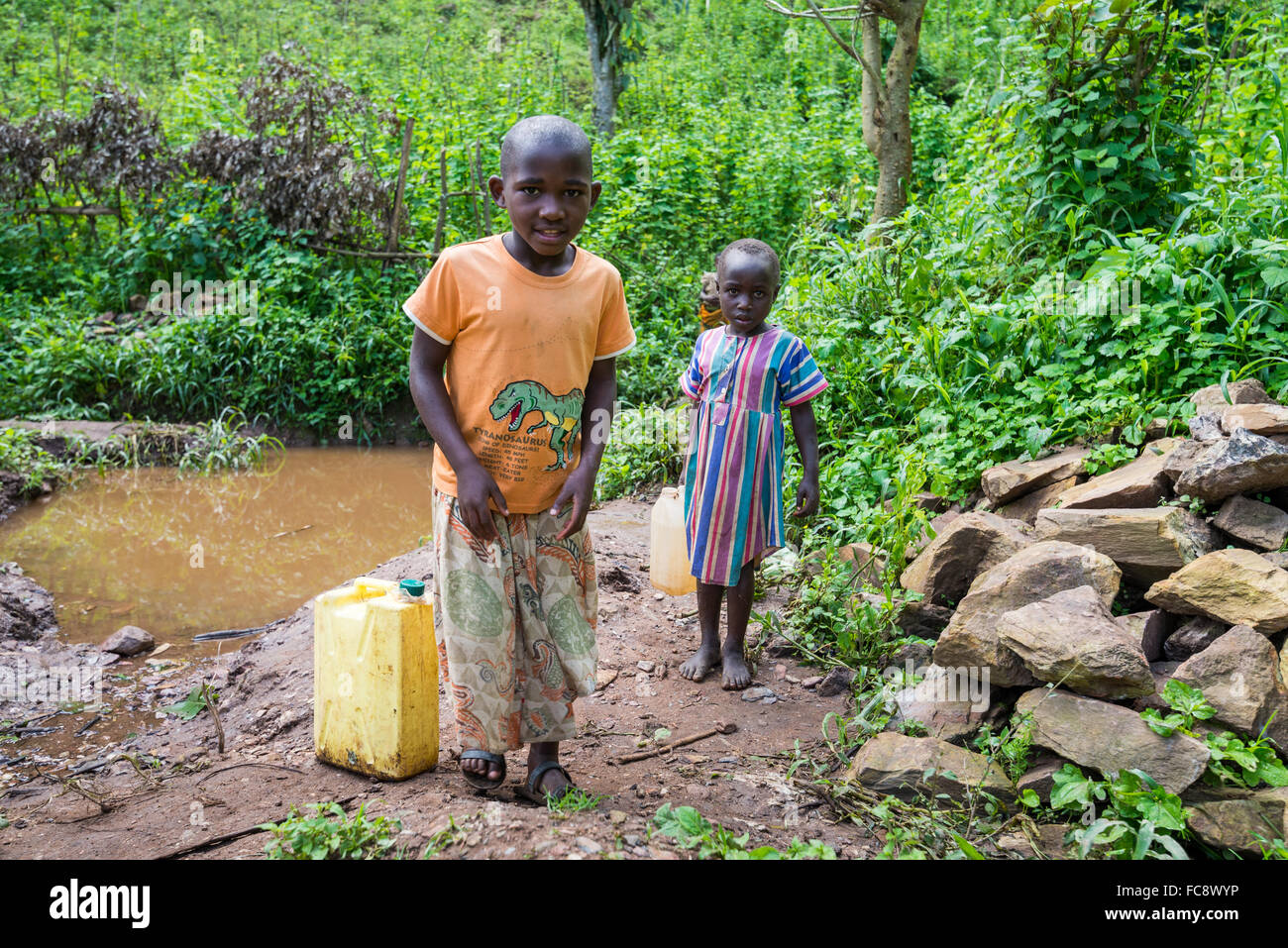 Children fetch fresh drinking water at a river, Kabala district,  Uganda, Africa Stock Photo
