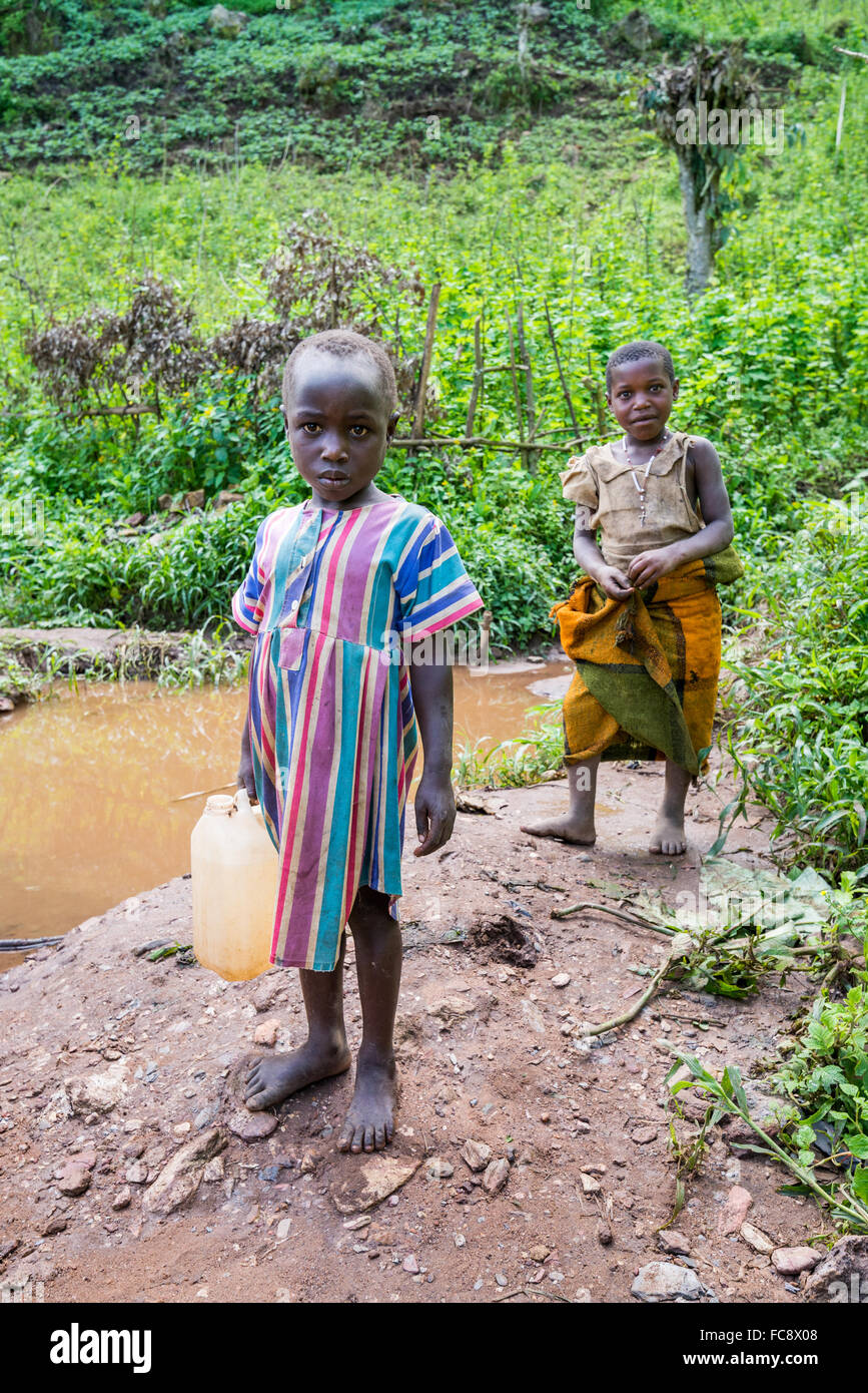 Children fetch fresh drinking water at a river, Kabala district,  Uganda, Africa Stock Photo
