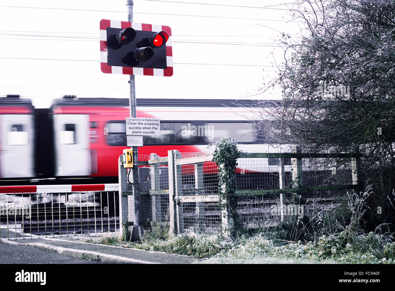 Train speeding past level crossing while lights on red. Small rural