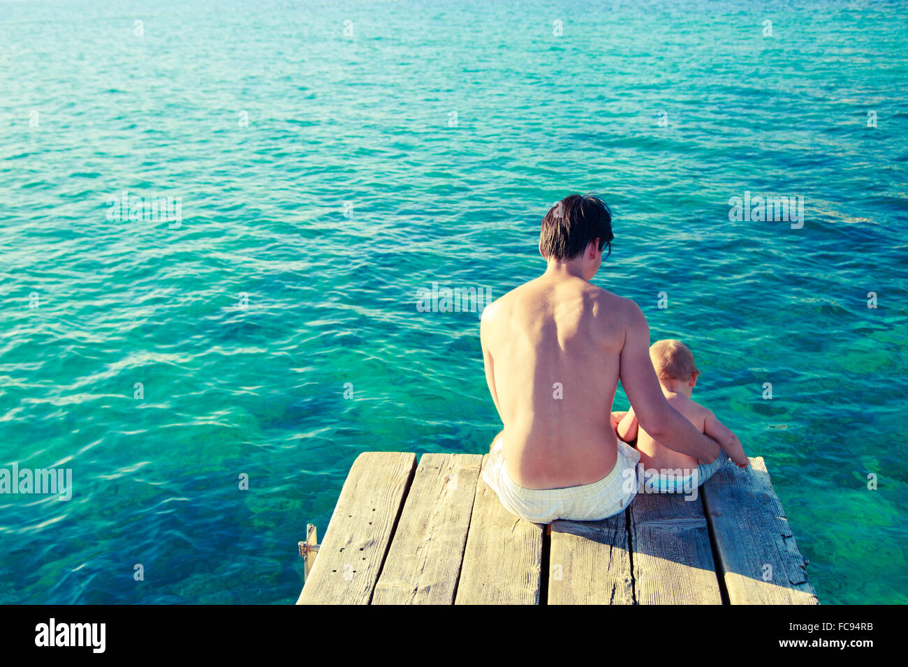 Young Father with His Son Relaxing by the Sea Stock Photo
