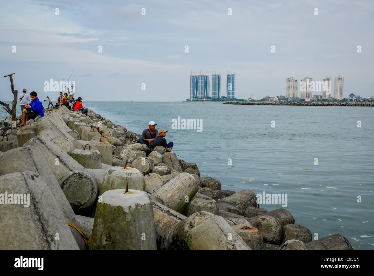 Local people spending a free time with fishing activity at tetrapod wave barriers in Jakarta, Indonesia. Stock Photo