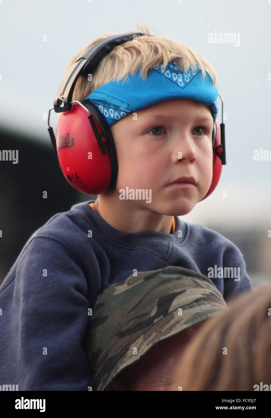 A boy wears ear defenders whilst watching a band perform on the main stage at the Y Not music festival England UK Stock Photo