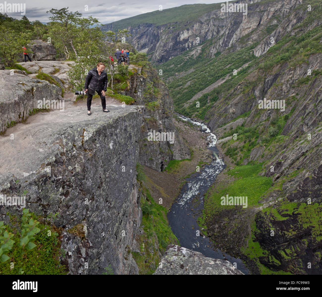 Vorningsfossen waterfall, Eidfjord, Hordaland, Norway Tourist looking over steep edge. Stock Photo