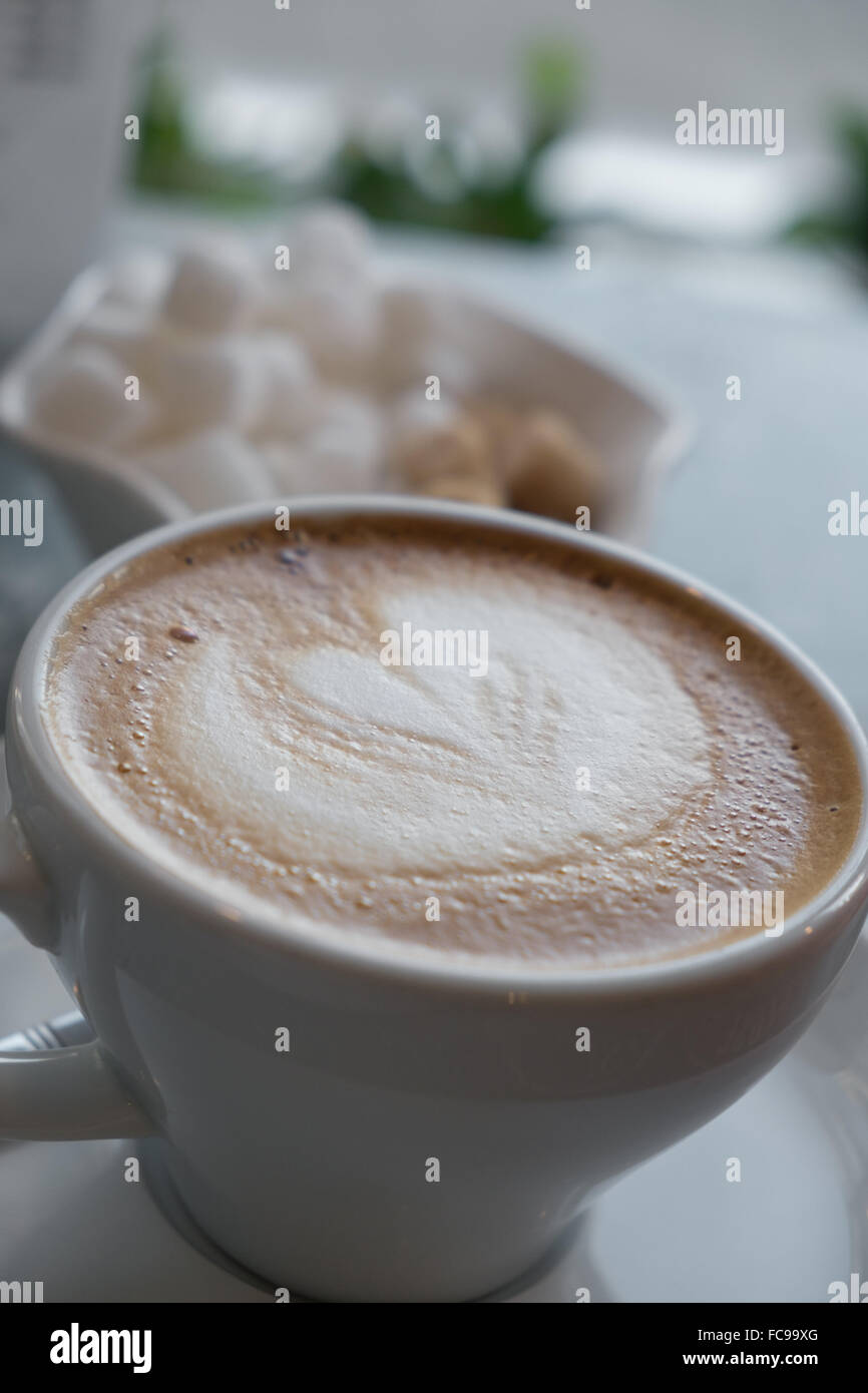 Latte with a bowl of sugar cubes on a café table Stock Photo