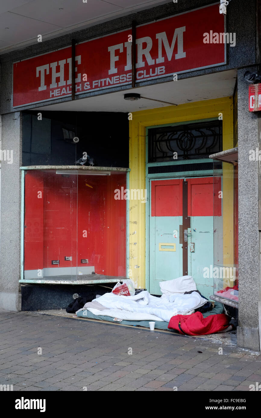 sleeping bags and blankets of homeless people stake out there patch in an empty closed shop doorway england uk Stock Photo