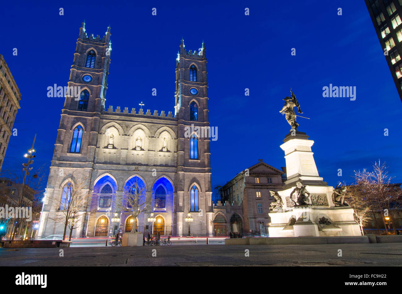 Notre-Dame Basilica’s Gothic Revival towers scratch the blue tinted skies over the 17th century Place d’Armes. Stock Photo