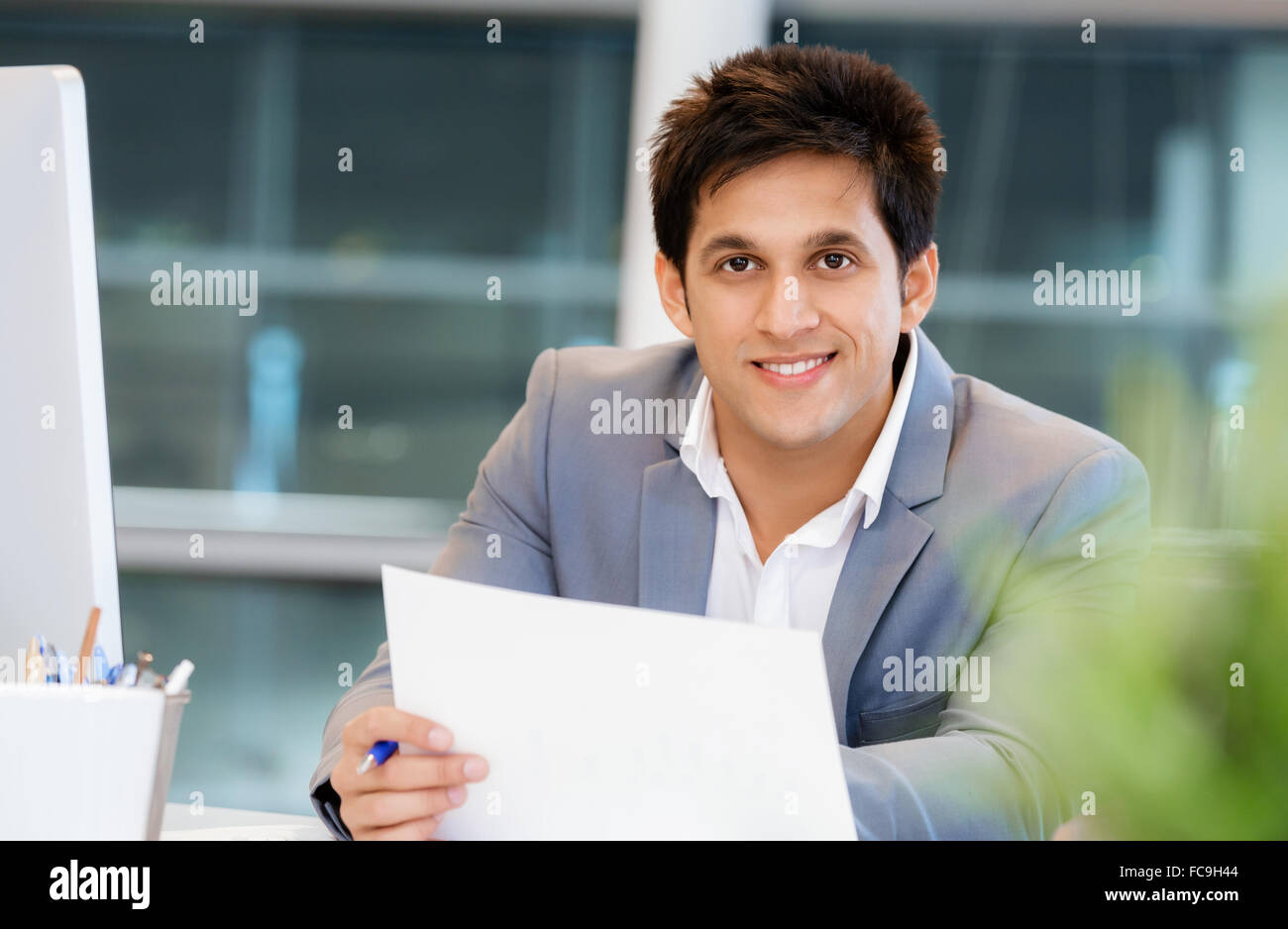 Businessman standing in office smiling at camera Stock Photo - Alamy