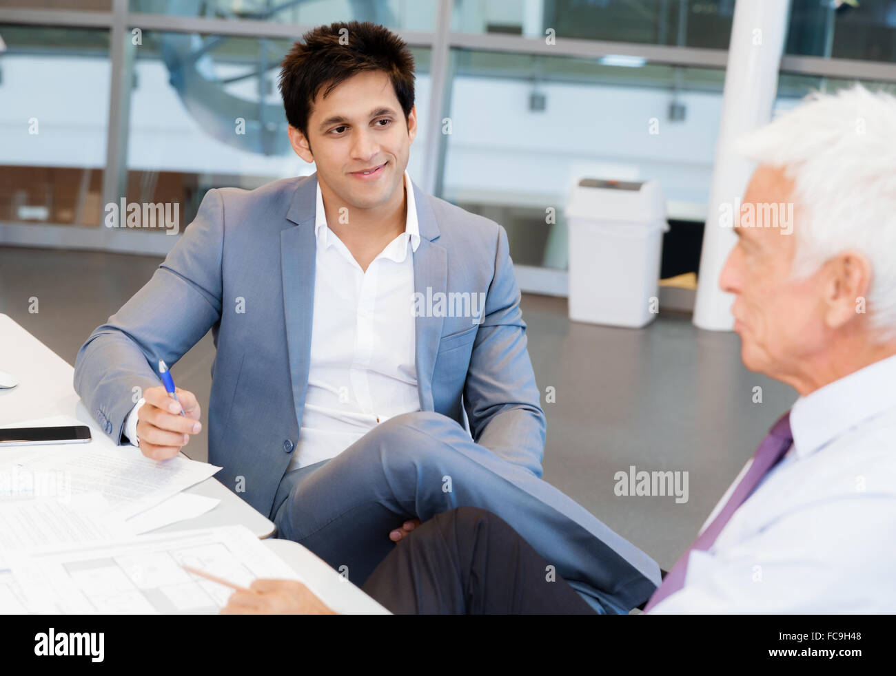 Businessman standing in office smiling at camera Stock Photo - Alamy
