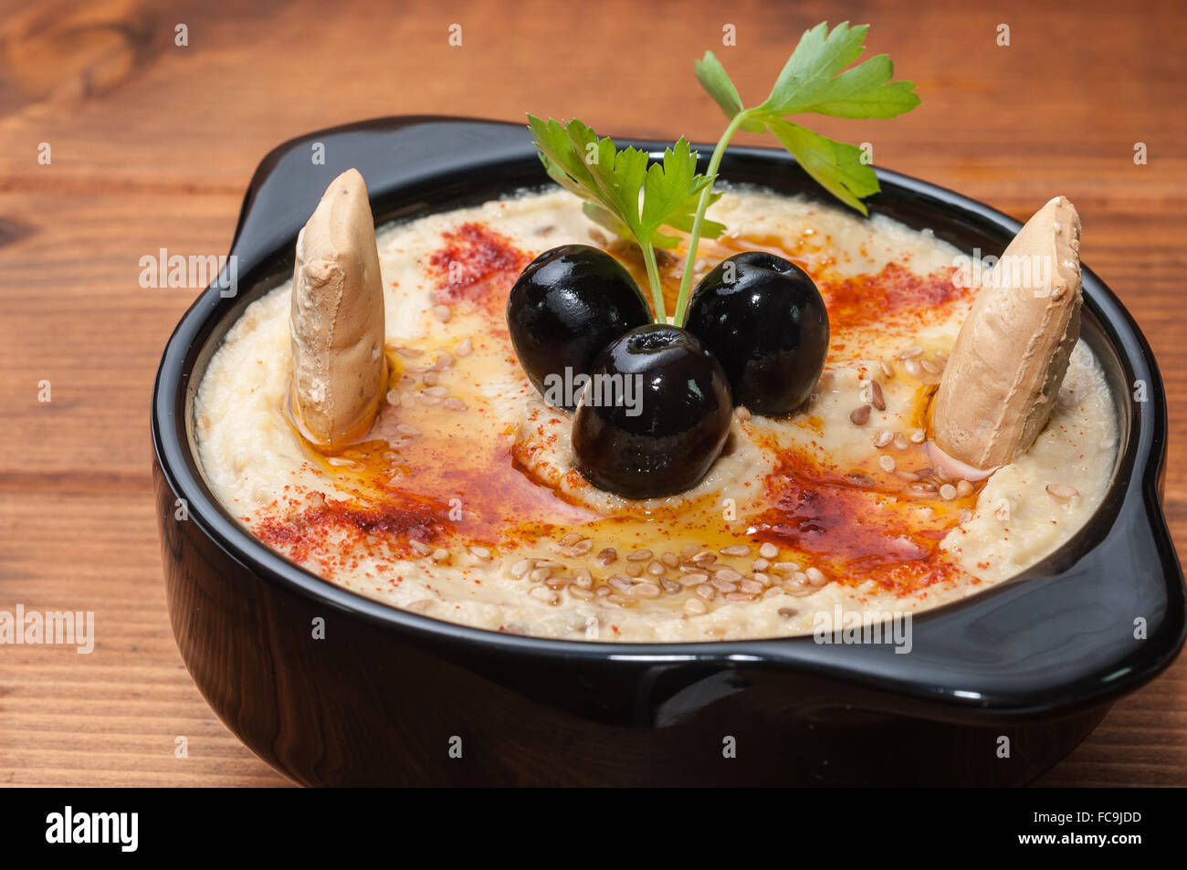 Hummus dish decorated with black olives Stock Photo Alamy