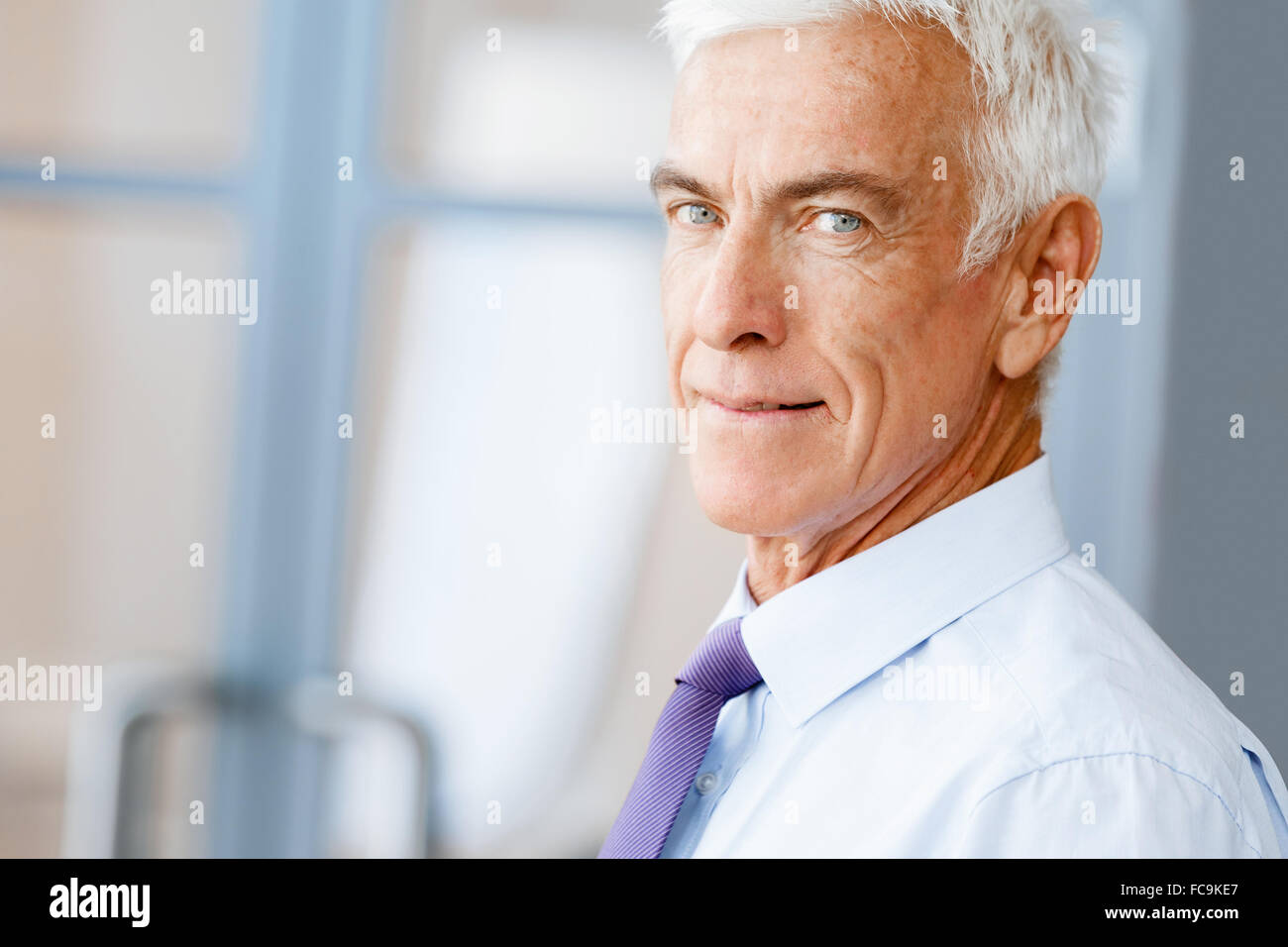 Businessman standing in office smiling at camera Stock Photo - Alamy