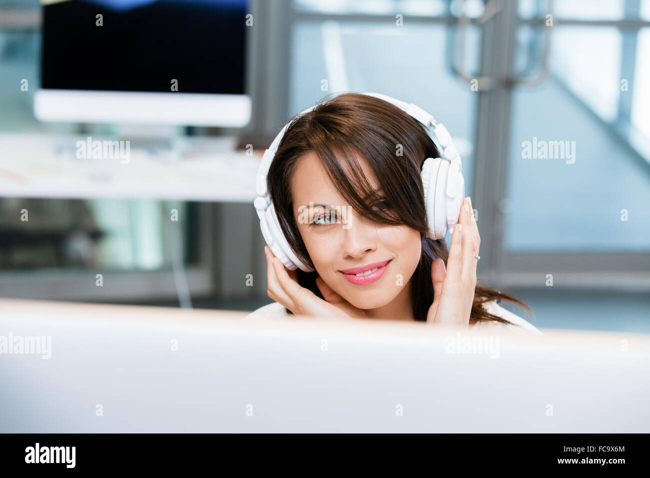 Woman in headphones sitting at desk in office Stock Photo - Alamy