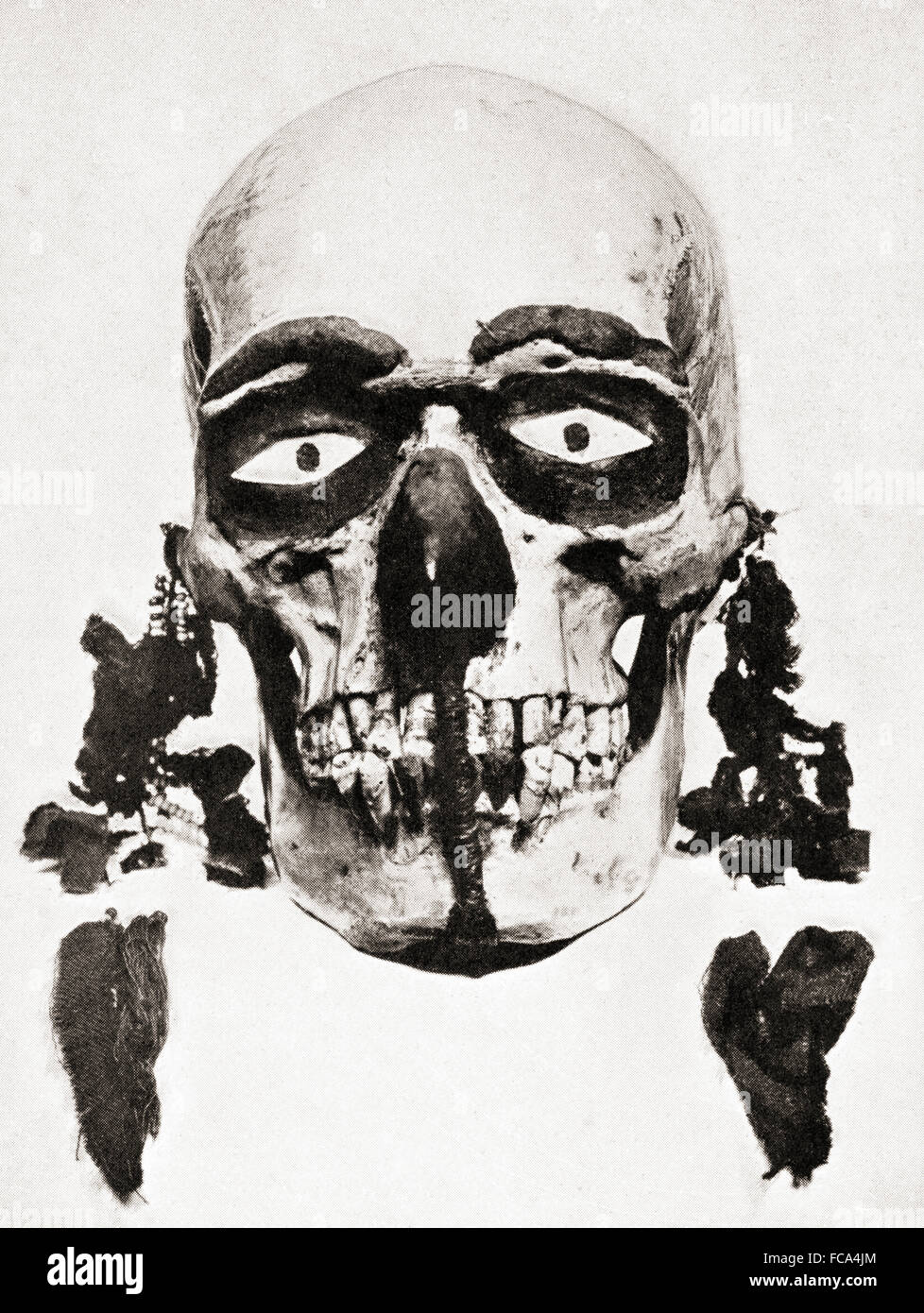A skull preserved and decorated and used for divination on the Torres Straits Islands, Papua New Guinea, Melanesia.  The inquirer would clean, paint and anoint the skull, enjoin it to speak the truth, put it near his head at night, go to sleep and dream and his actions would be based on the dream.  From a nineteenth century photograph. Stock Photo