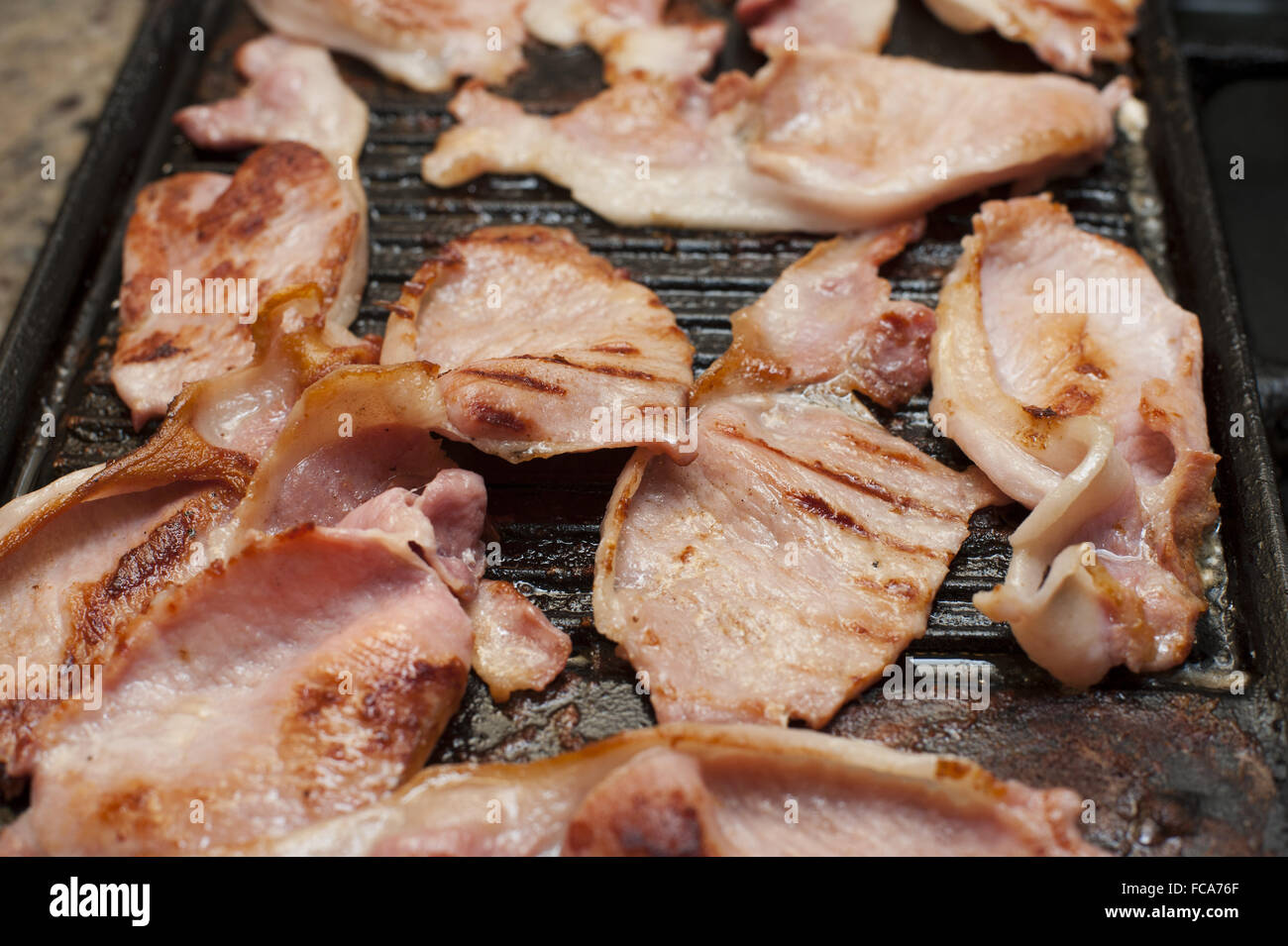 Rashers of smoked bacon on a griddle Stock Photo