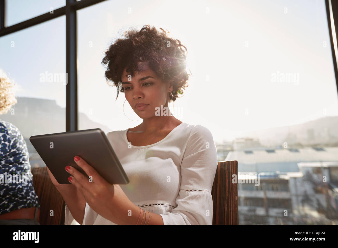Portrait of young woman busy working on digital tablet on a sunny day. Attractive african woman surfing internet on tablet compu Stock Photo