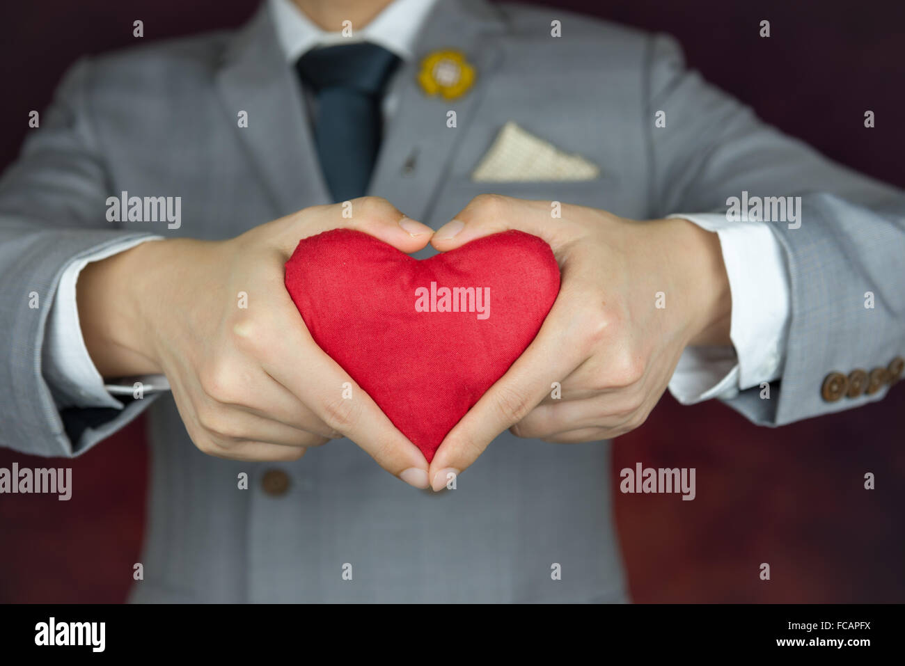 red heart in hands with heart gesture, valentine's concept, man in grey suit Stock Photo