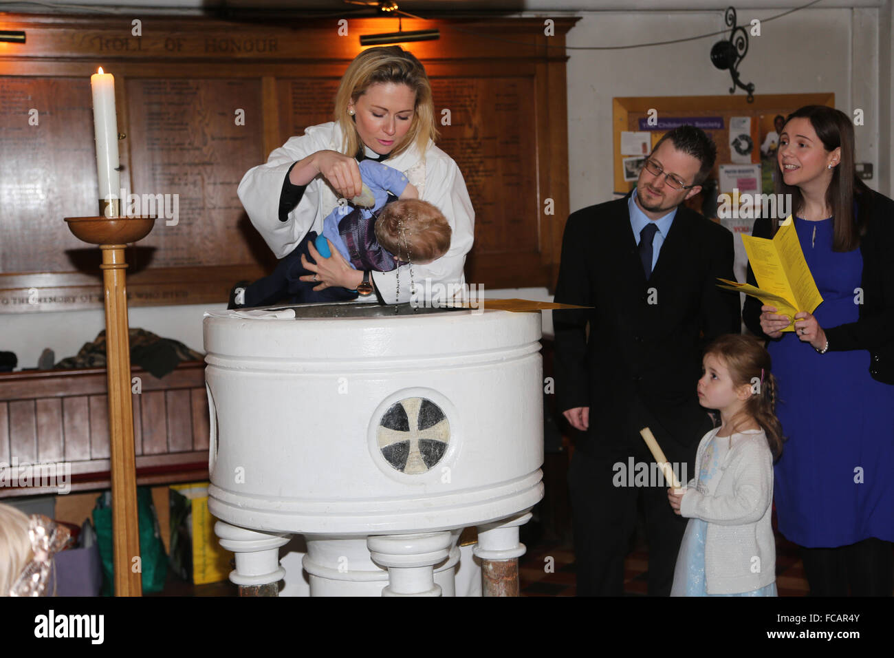 Christening At St Mary's Church Caterham On The Hill Surrey England Female Priest Pouring Holy Water On Baby Boy Using Shell Stock Photo