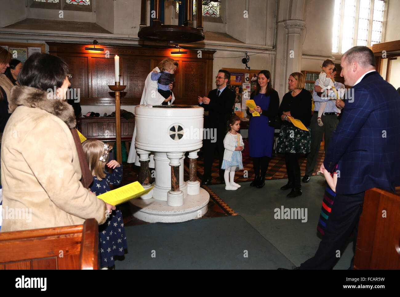 Christening At St Mary's Church Caterham On The Hill Surrey England Female Priest Holding Baby Boy By Font Stock Photo