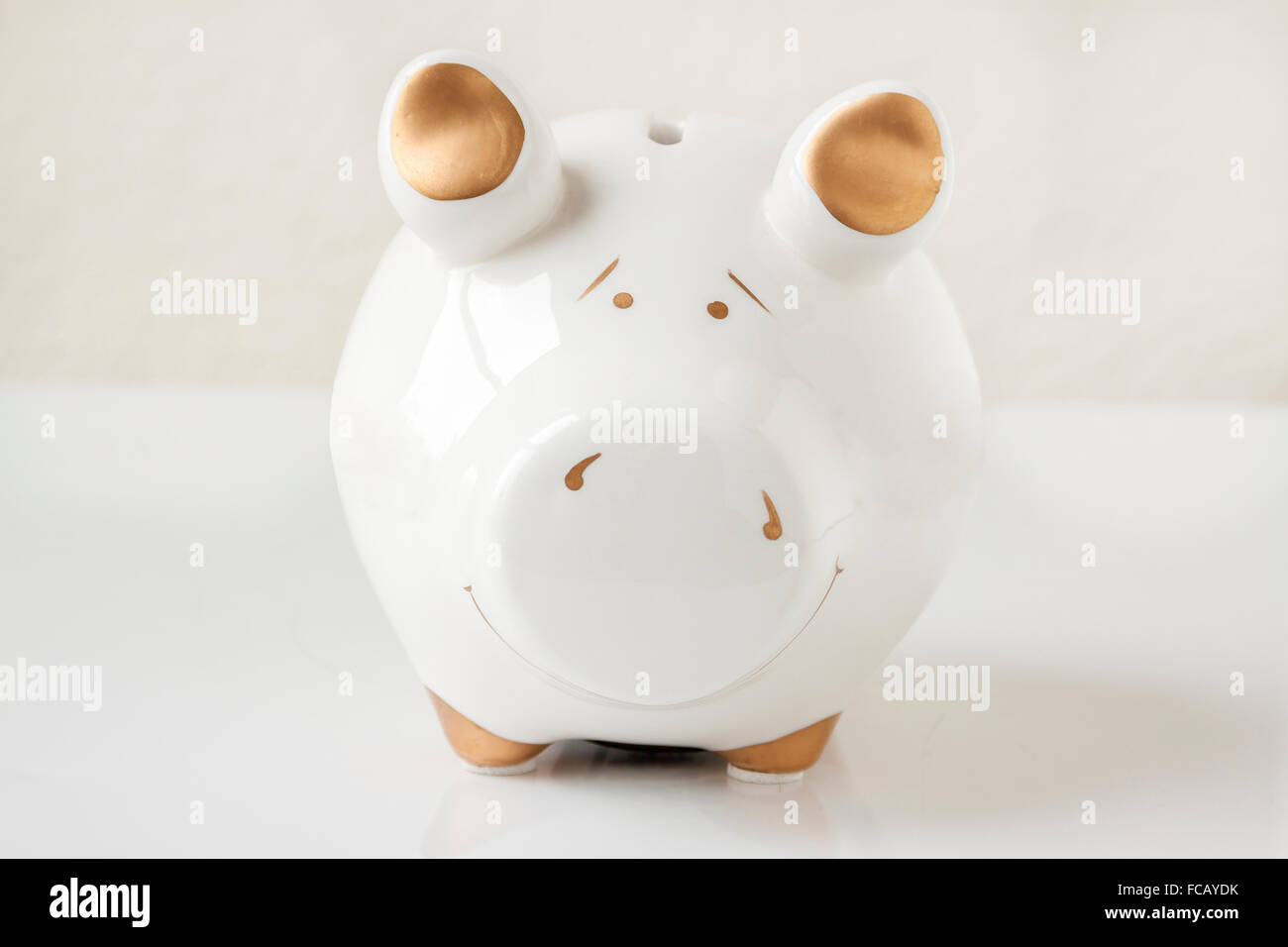 A white and gold piggy bank on a white background Stock Photo - Alamy
