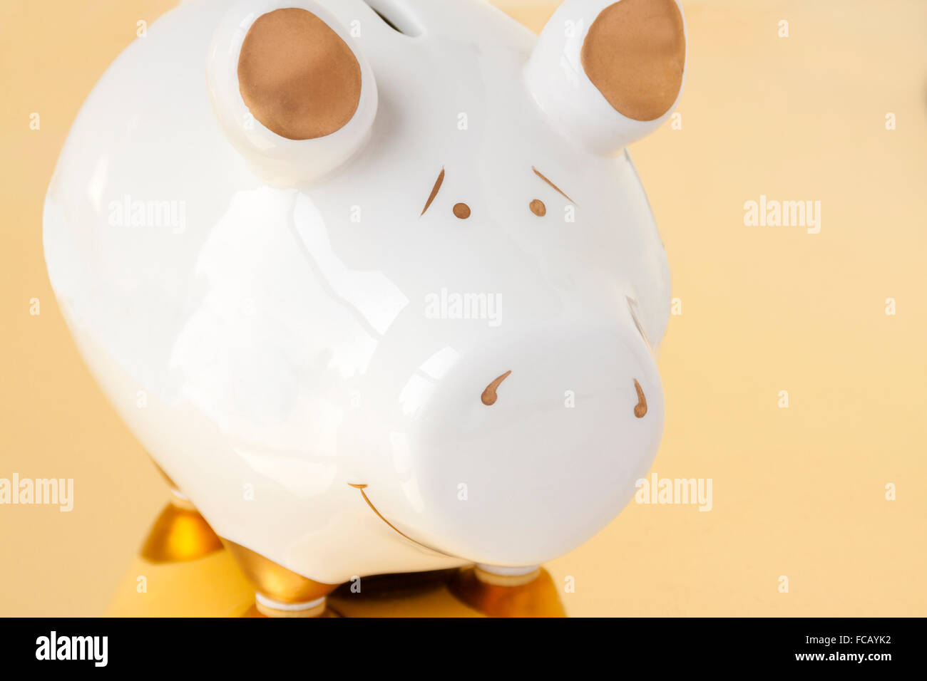 A white and gold piggy bank on a gold background Stock Photo - Alamy