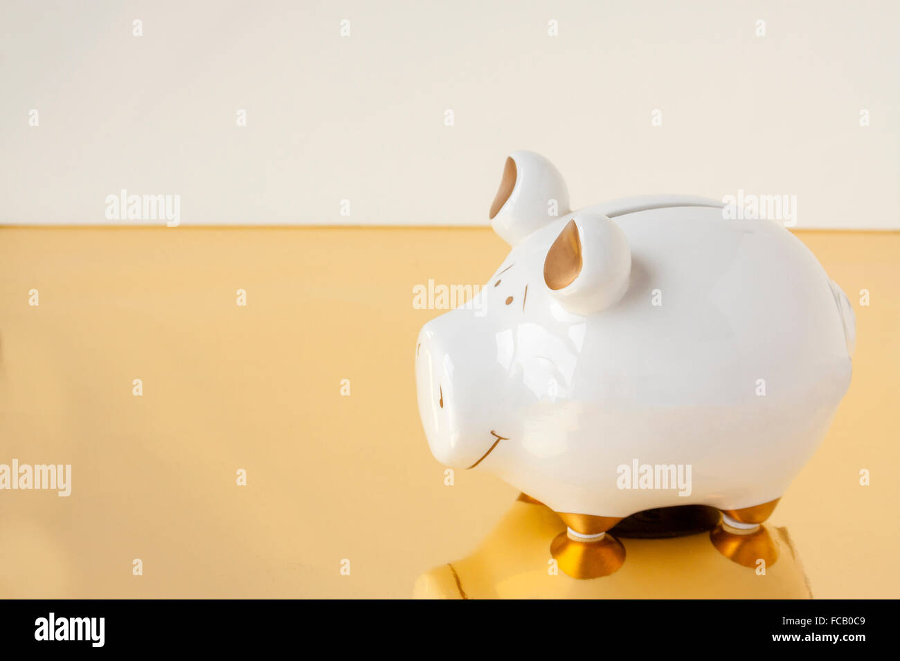 A white and gold piggy bank on a white and gold background Stock Photo ...